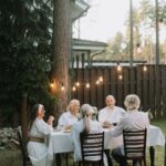 Suvine õhtusöök õues valgusketi all pika laua ääres